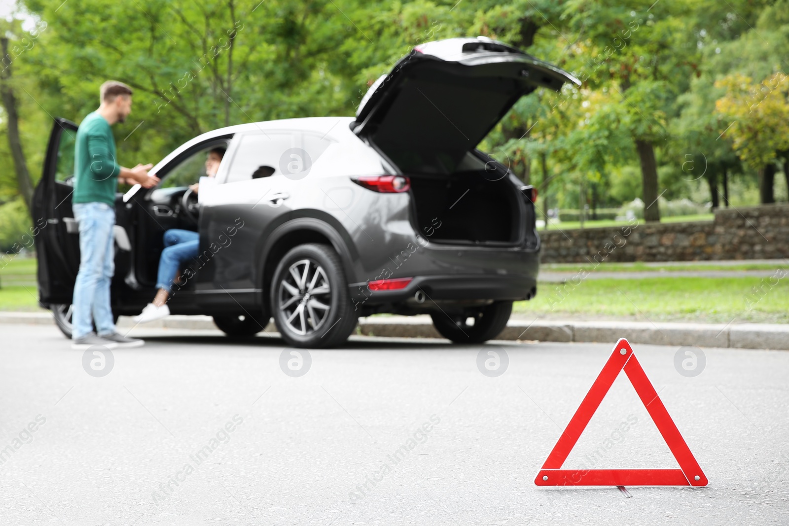 Photo of Emergency stop sign with people and broken car on background