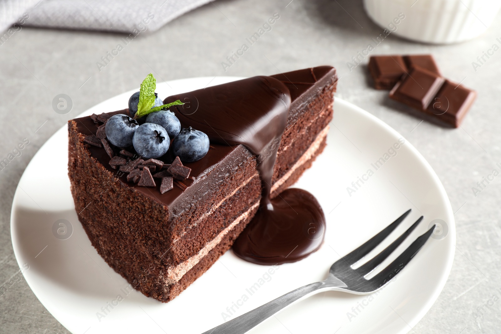 Photo of Delicious fresh chocolate cake with blueberries on light table, closeup