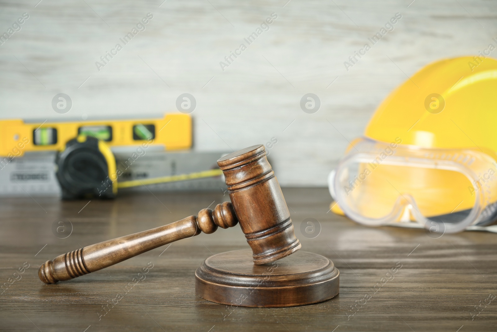 Photo of Construction and land law concepts. Judge gavel, protective helmet with safety goggles on wooden table