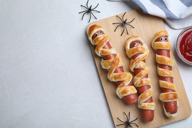 Cute sausage mummies served on white table, flat lay with space for text. Halloween party food