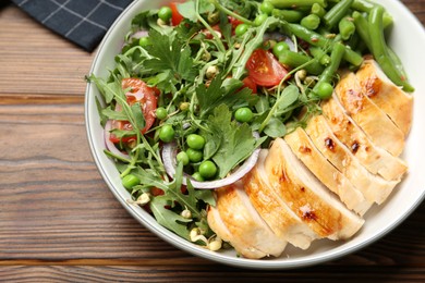 Photo of Healthy meal. Tasty salad and chicken breast in bowl on wooden table