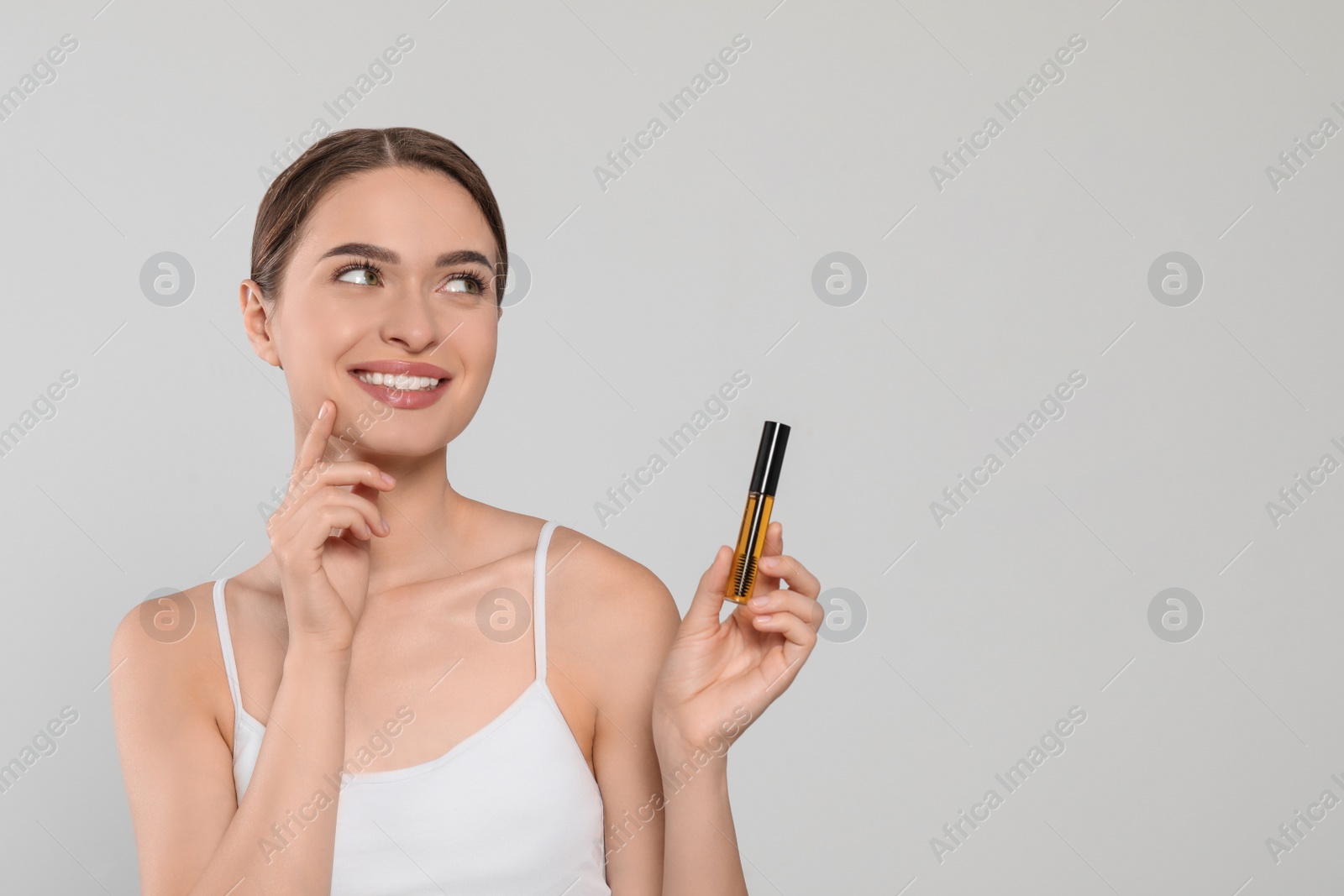 Photo of Young woman with eyelash oil on white background, space for text