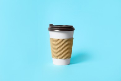 Photo of Takeaway paper coffee cup with cardboard sleeve on light blue background