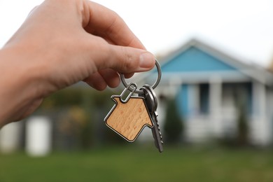 Photo of Woman holding house keys outdoors, closeup. Real estate agent