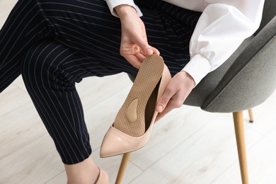 Photo of Woman putting orthopedic insole into high heel shoe, closeup. Foot care