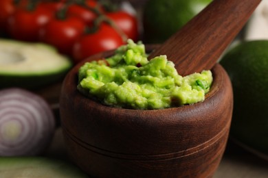 Mortar with delicious guacamole and ingredients, closeup