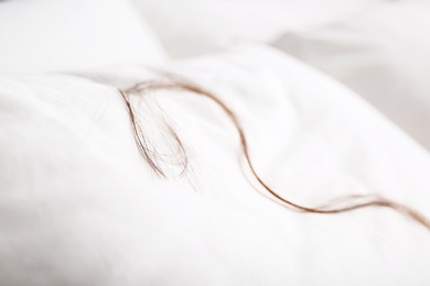 Photo of White pillow with fallen long hair on bed