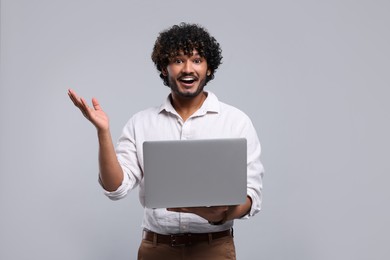 Surprised man with laptop on light grey background