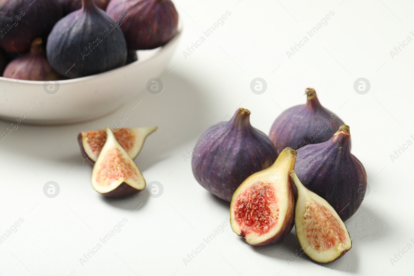 Photo of Whole and cut tasty fresh figs on white table