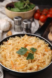 Photo of Frying pan with sauerkraut on brown table, closeup
