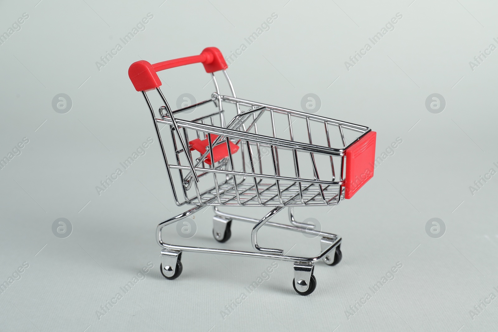 Photo of Small metal shopping cart on light background