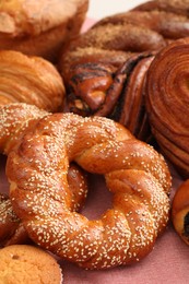 Photo of Different tasty freshly baked pastries on pink tablecloth, closeup