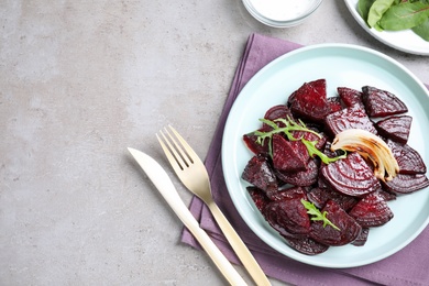 Roasted beetroot slices with onion and arugula served on light grey table, flat lay. Space for text