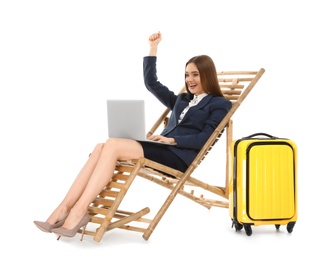 Young businesswoman with laptop and suitcase on sun lounger against white background. Beach accessories