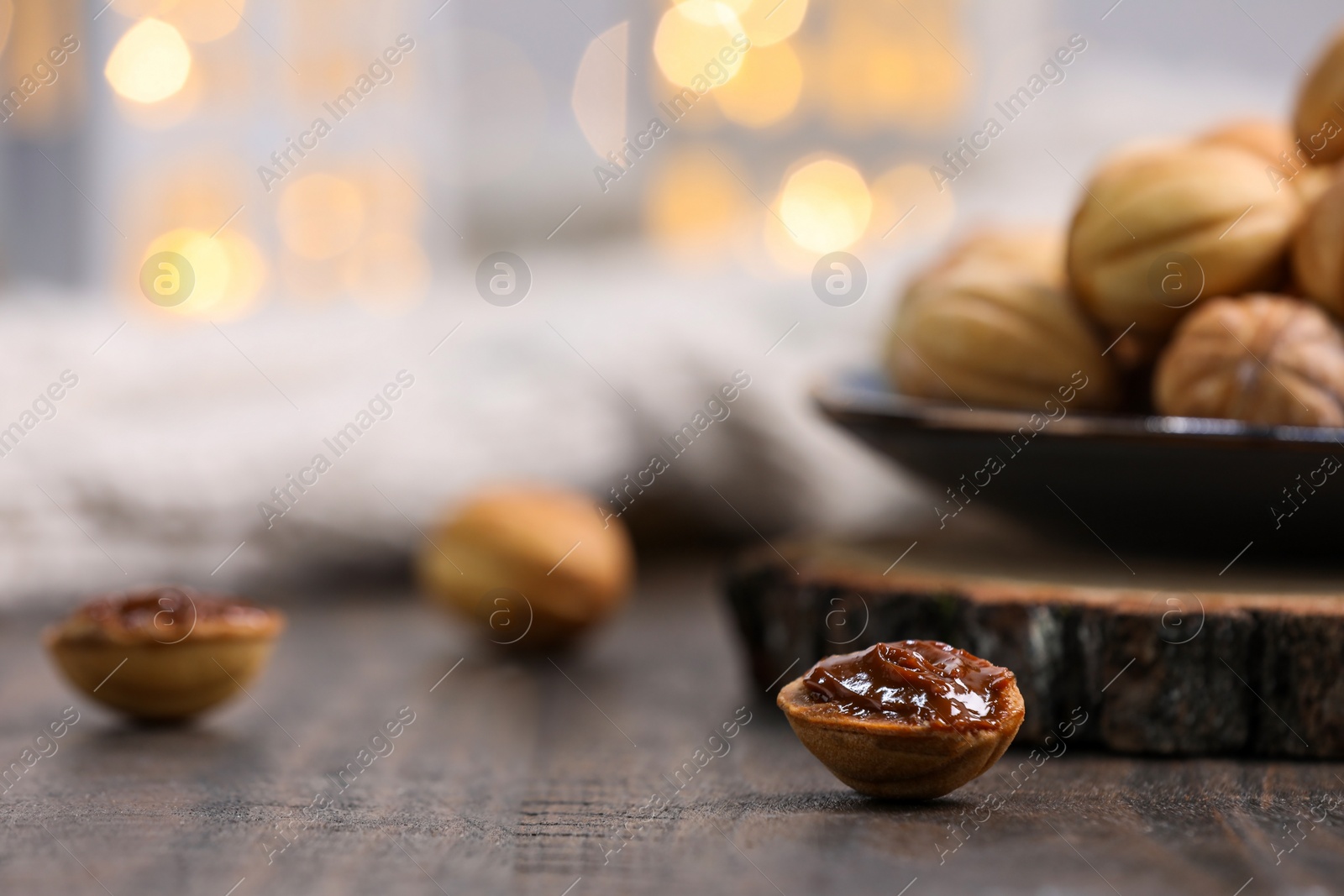 Photo of Homemade walnut shaped cookies with boiled condensed milk on wooden table, space for text. Bokeh effect