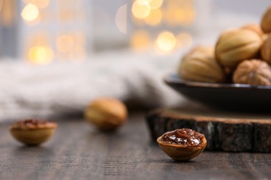 Homemade walnut shaped cookies with boiled condensed milk on wooden table, space for text. Bokeh effect