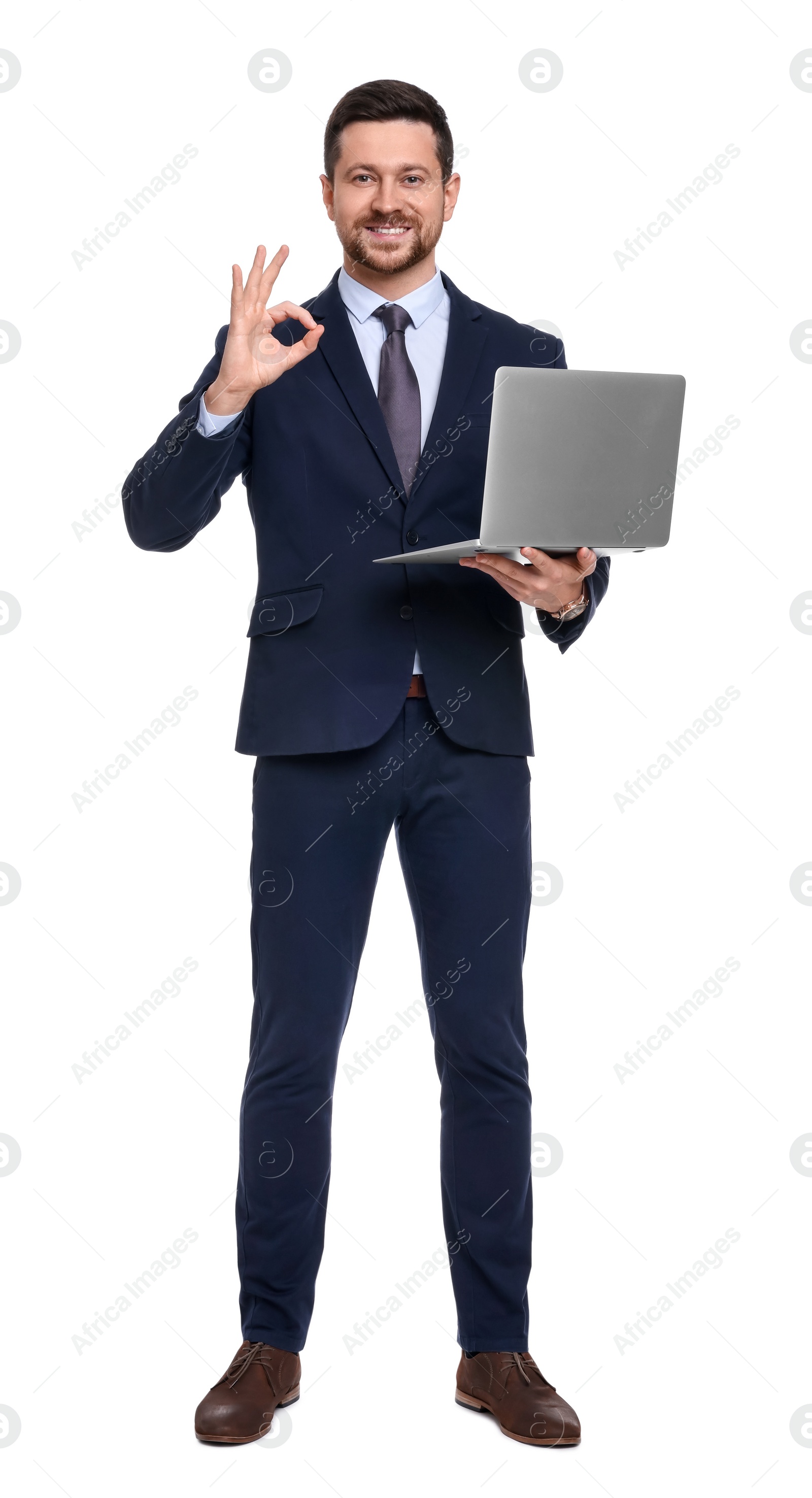 Photo of Handsome bearded businessman in suit with laptop showing OK gesture on white background