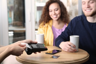 Clients using credit card machine for non cash payment in cafe