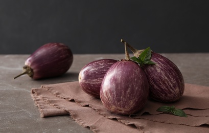 Photo of Ripe eggplants and basil on brown marble table, closeup