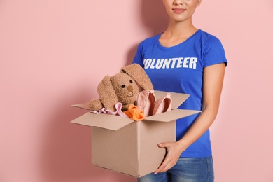 Photo of Female volunteer holding box with donations on color background