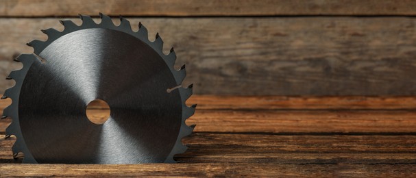 Image of Saw disk on wooden background, space for text. Carpenter's tool. Banner design