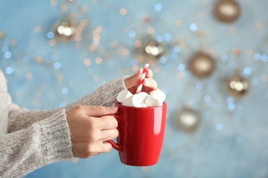 Photo of Young woman with delicious hot cocoa drink on blurred background, closeup