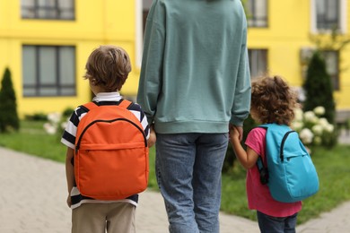 Woman and her children on their way to kindergarten outdoors, back view