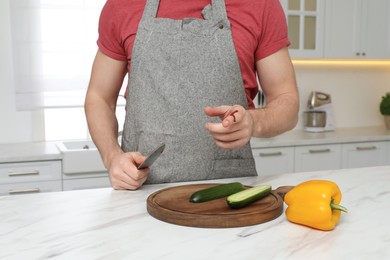 Photo of Man cut finger with knife while cooking at white marble table in kitchen, closeup