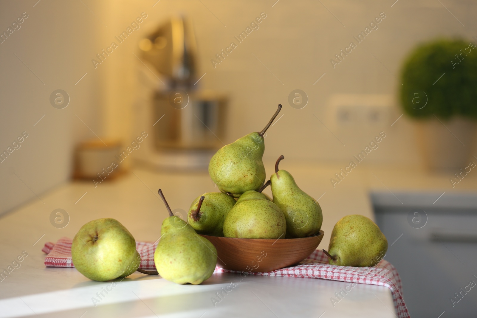 Photo of Fresh ripe pears on white countertop in kitchen