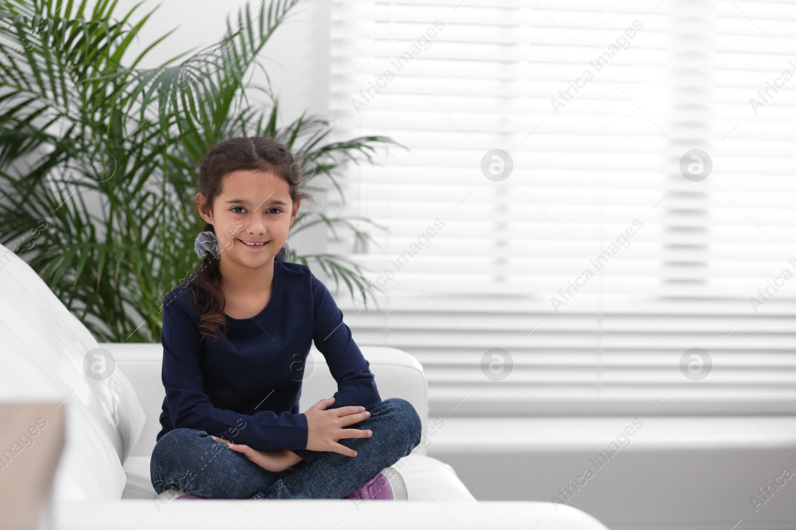 Photo of Cute little girl on sofa in living room