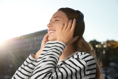 Smiling woman in headphones listening to music outdoors