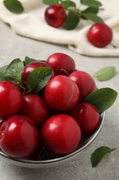 Photo of Delicious ripe cherry plums with leaves on light table