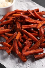 Photo of Delicious sweet potato fries on parchment paper, closeup