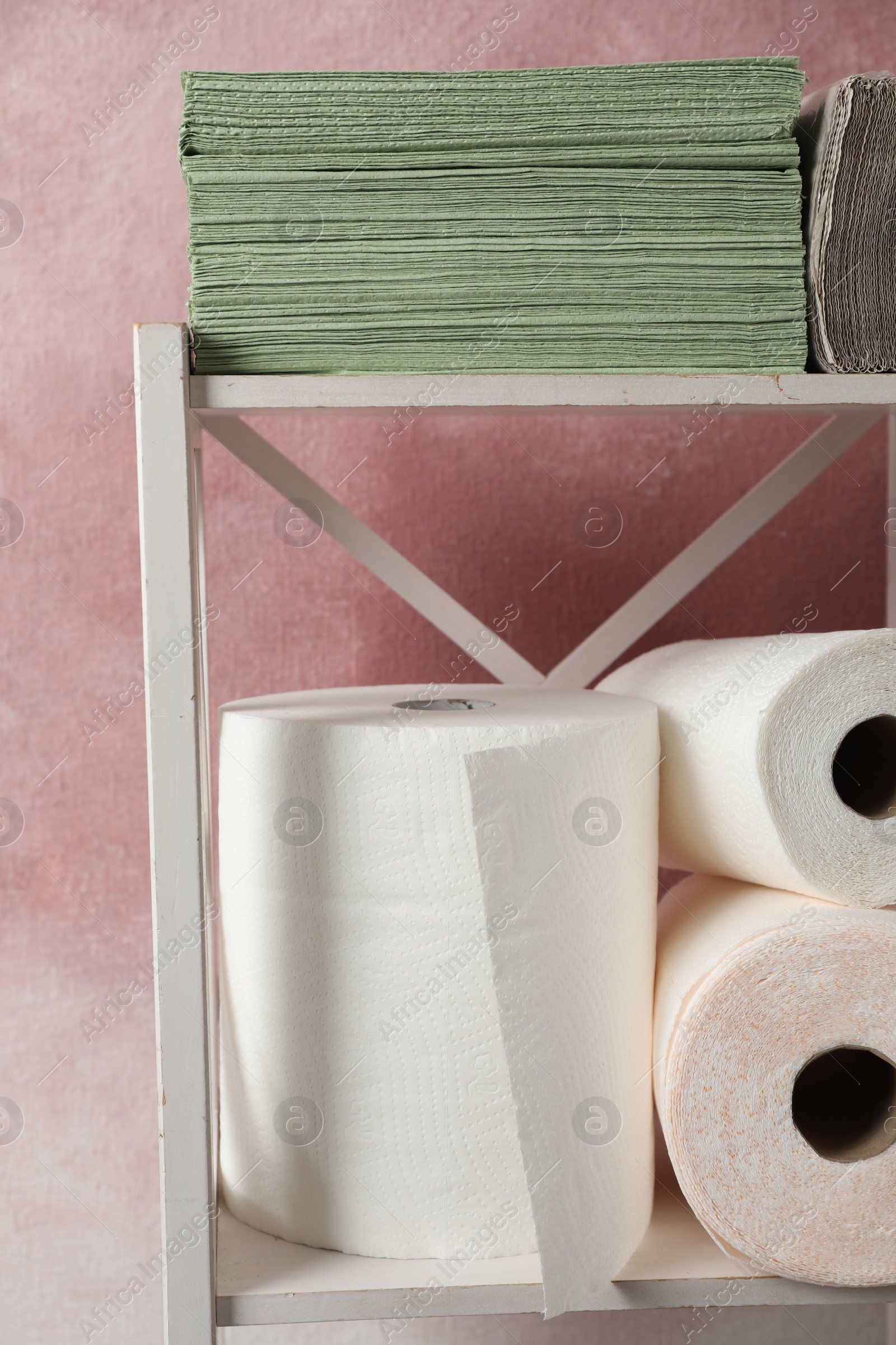 Photo of Shelving unit with paper towels near pink wall