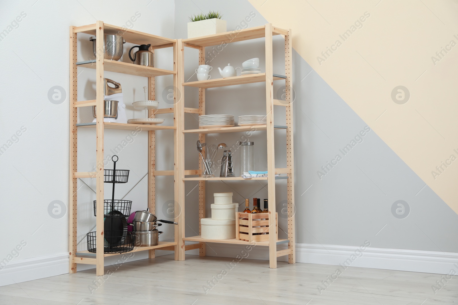 Photo of Wooden shelving units with kitchenware near color wall, space for text. Stylish room interior