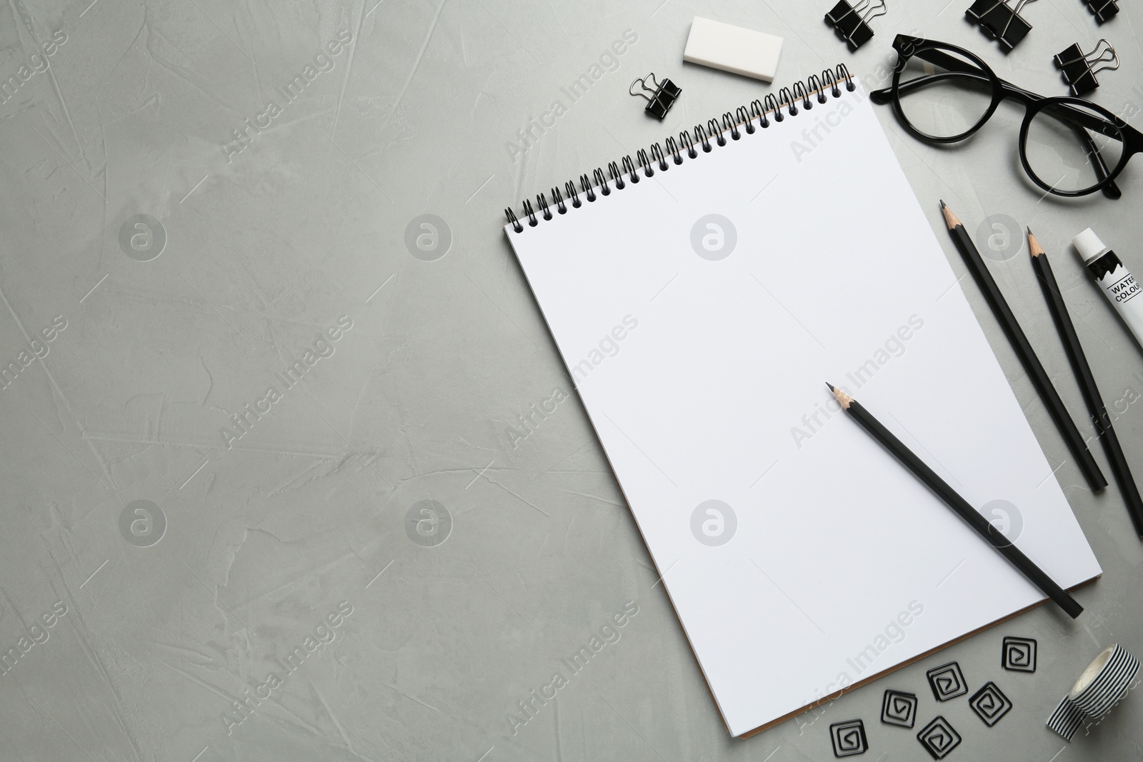 Photo of Flat lay composition with sketchbook, glasses and stationary on light grey table, space for text