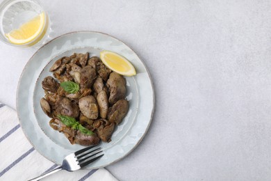 Photo of Delicious fried chicken liver with onion served on light table, flat lay. Space for text