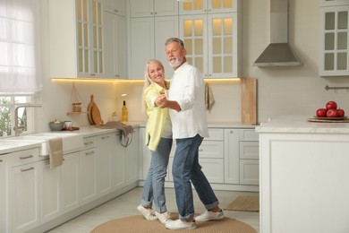 Photo of Happy senior couple dancing together in kitchen