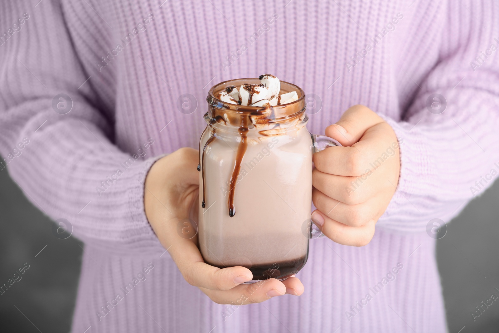 Photo of Woman holding jar with chocolate milk and marshmallows, closeup