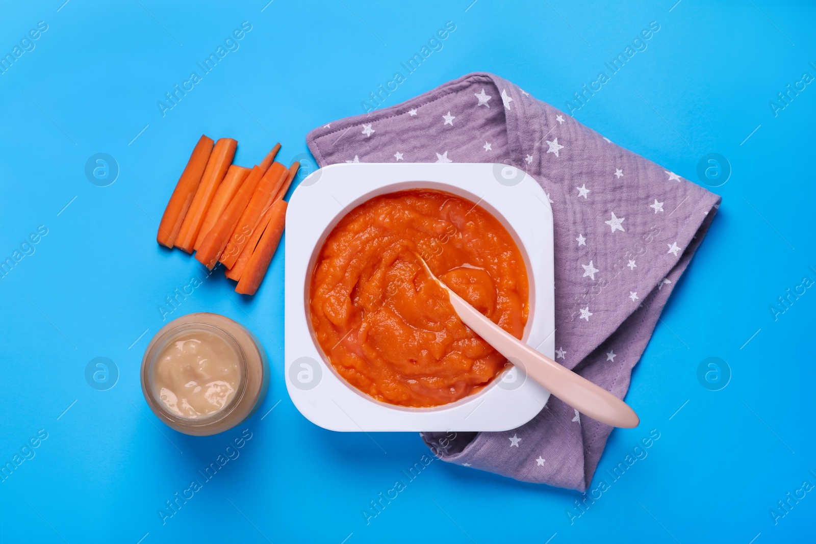 Photo of Healthy baby food and carrot on light blue background, flat lay