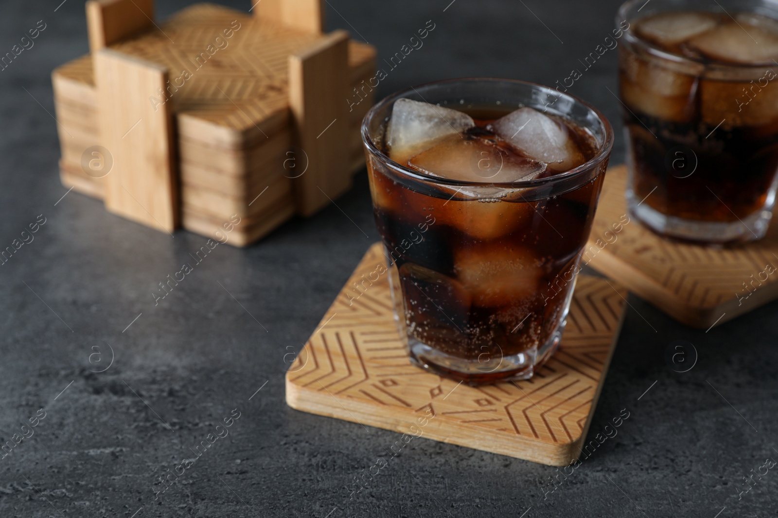 Photo of Glasses of cold drink and stylish cup coasters on grey table, space for text