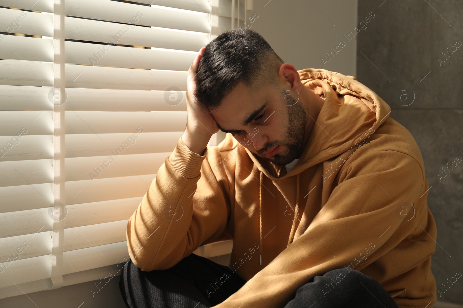 Photo of Sad young man and sitting near window