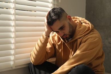 Sad young man and sitting near window