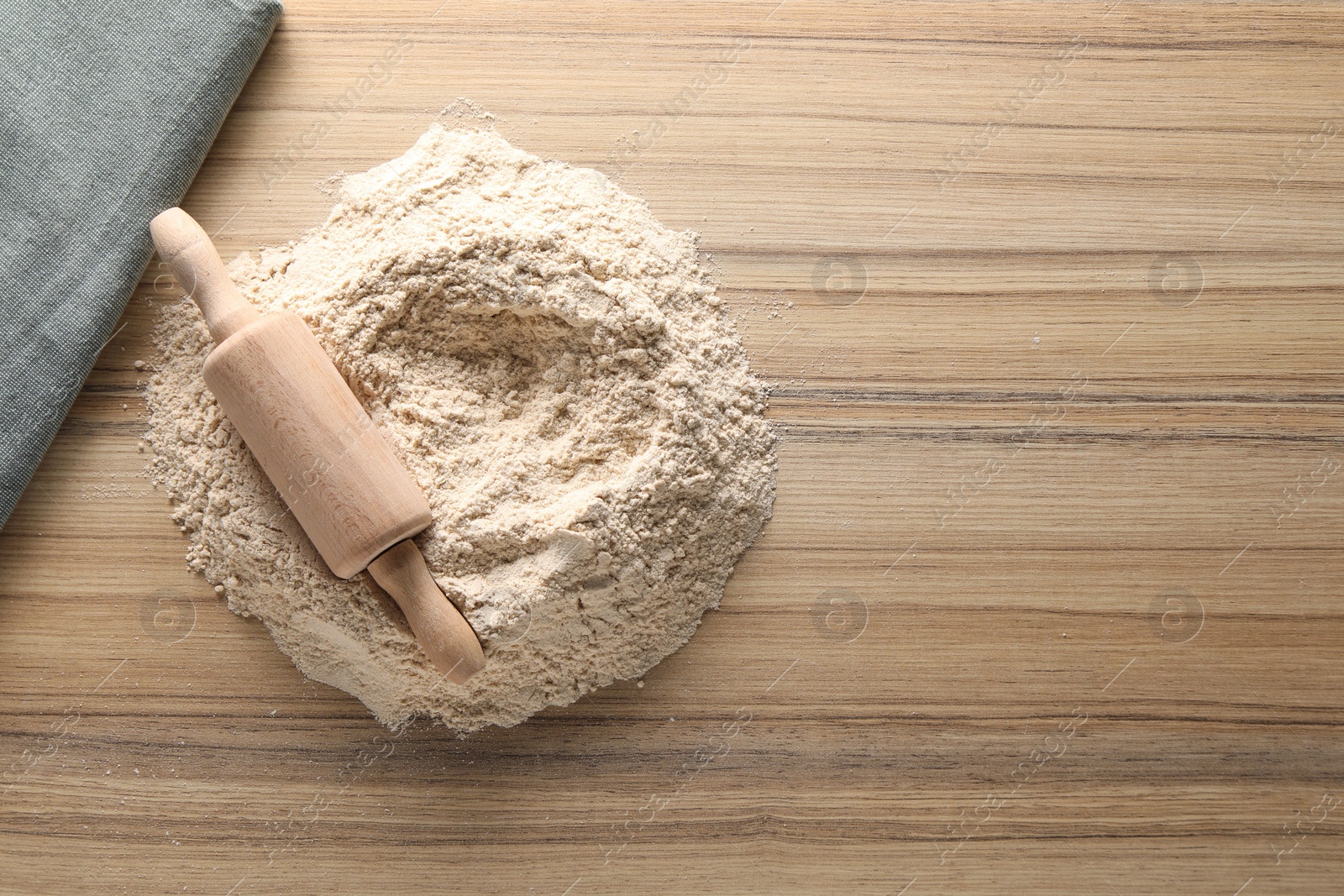 Photo of Pile of flour and rolling pin on wooden table, top view. Space for text