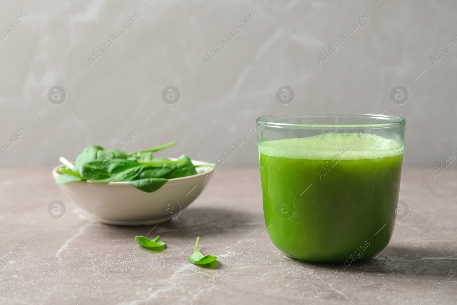 Photo of Glass with delicious detox juice and spinach on table