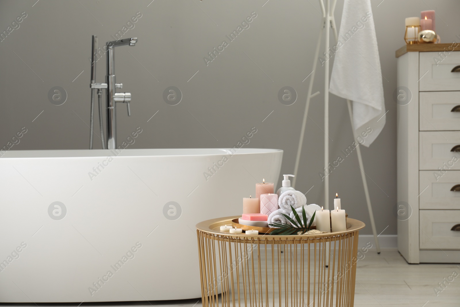 Photo of Stylish bathroom interior with ceramic tub and spa products on table