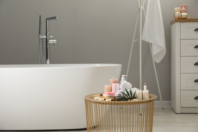 Photo of Stylish bathroom interior with ceramic tub and spa products on table