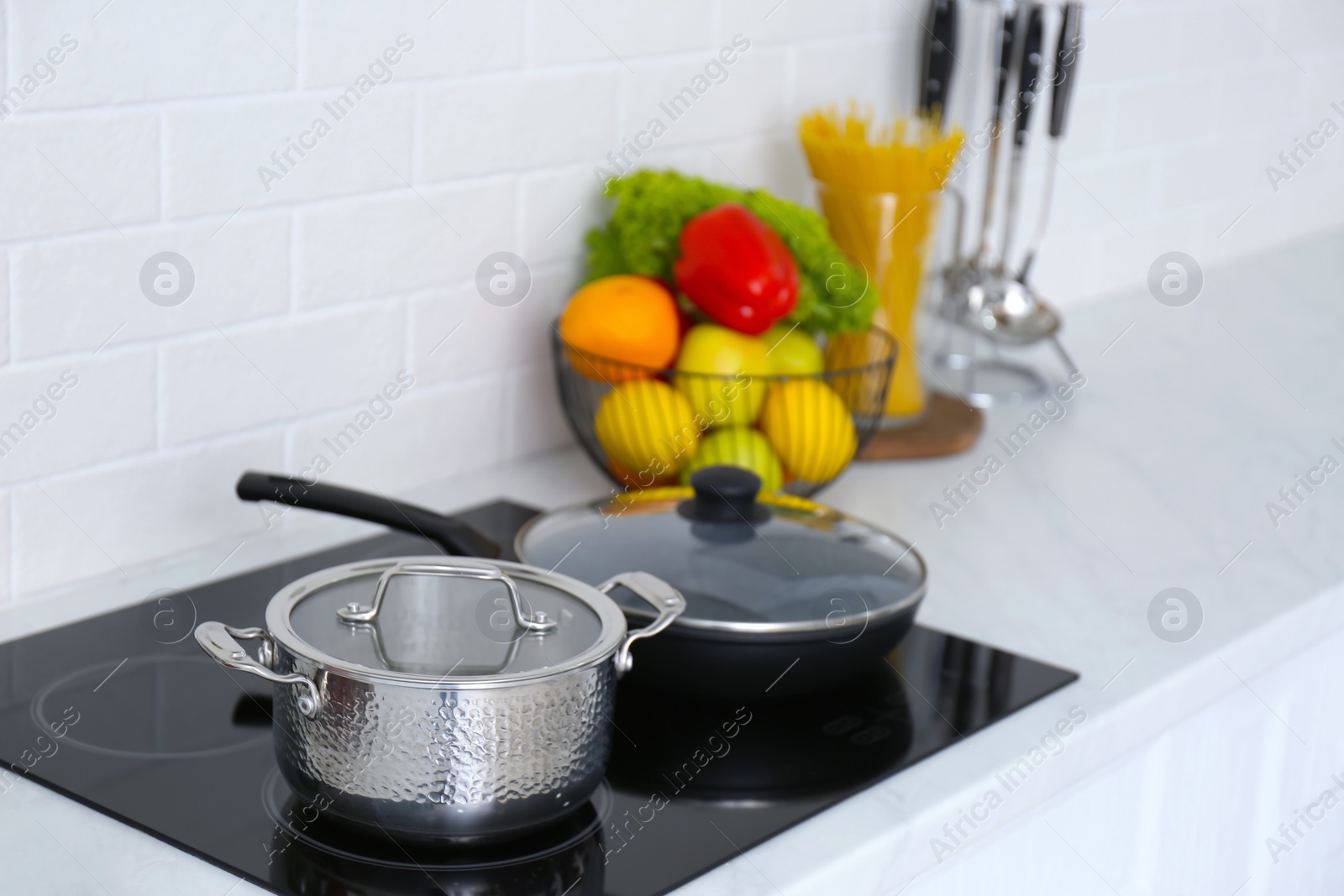 Photo of Saucepot and frying pan on induction stove in kitchen