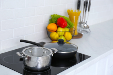 Saucepot and frying pan on induction stove in kitchen