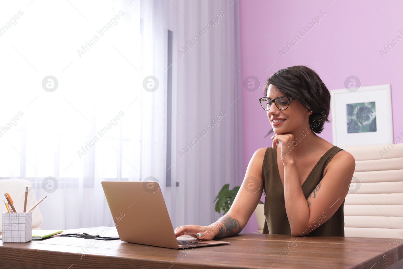 Photo of Young woman with modern laptop at desk in home office